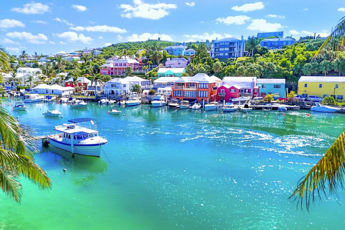 Boats moored in turquoise water below pastel Bermuda homes
